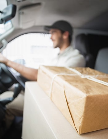 Paketlieferung im Fahrzeug, Fahrer bei der Zustellung, nachhaltiger Versand, E-Commerce, grüne Versandlösungen.