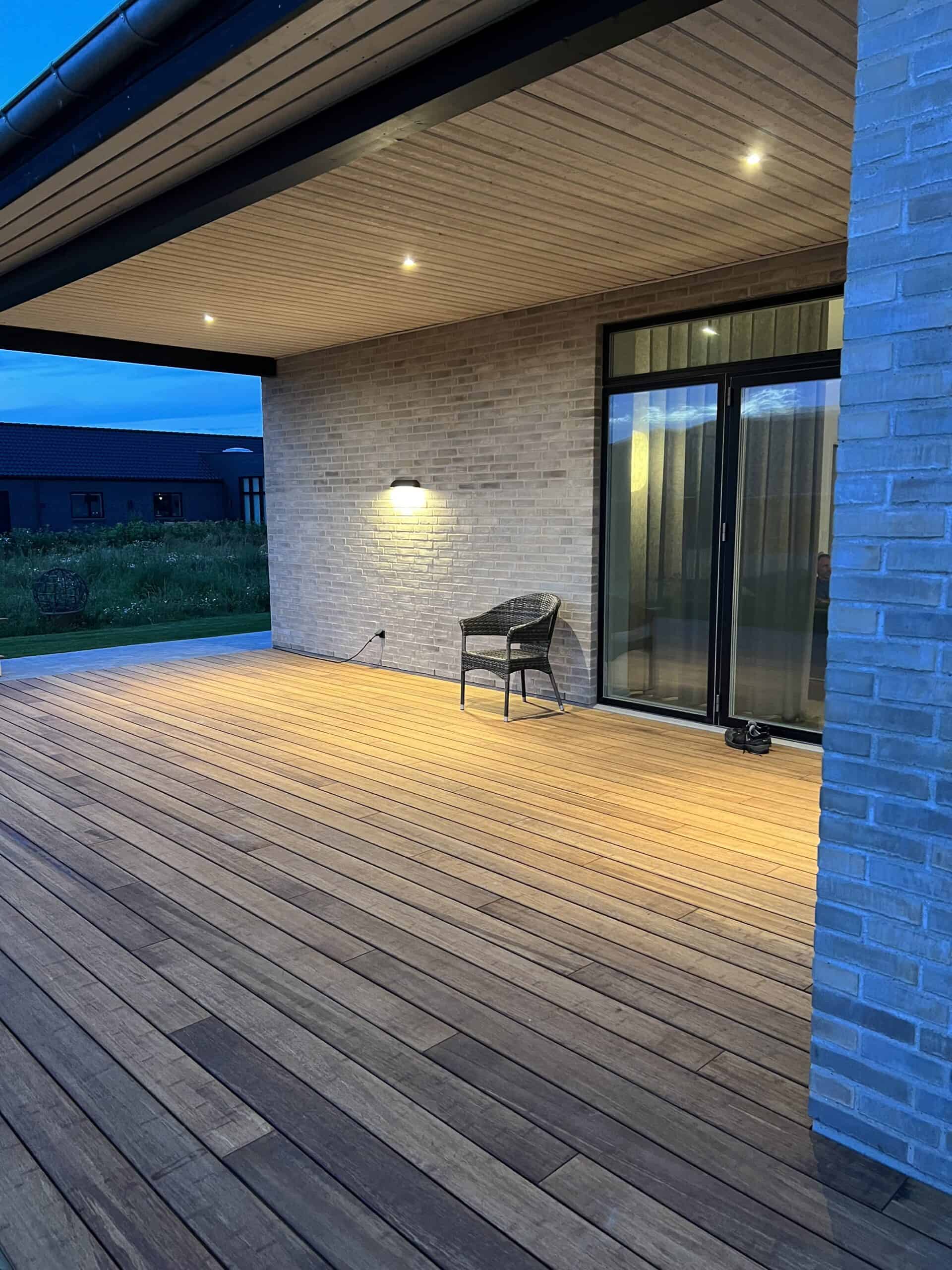 Hochwertige Holzterrasse im modernen Haus, warmes Licht, stilvolle Außenveranda, Natur in Innen- und Außenbereich perfekt kombiniert.