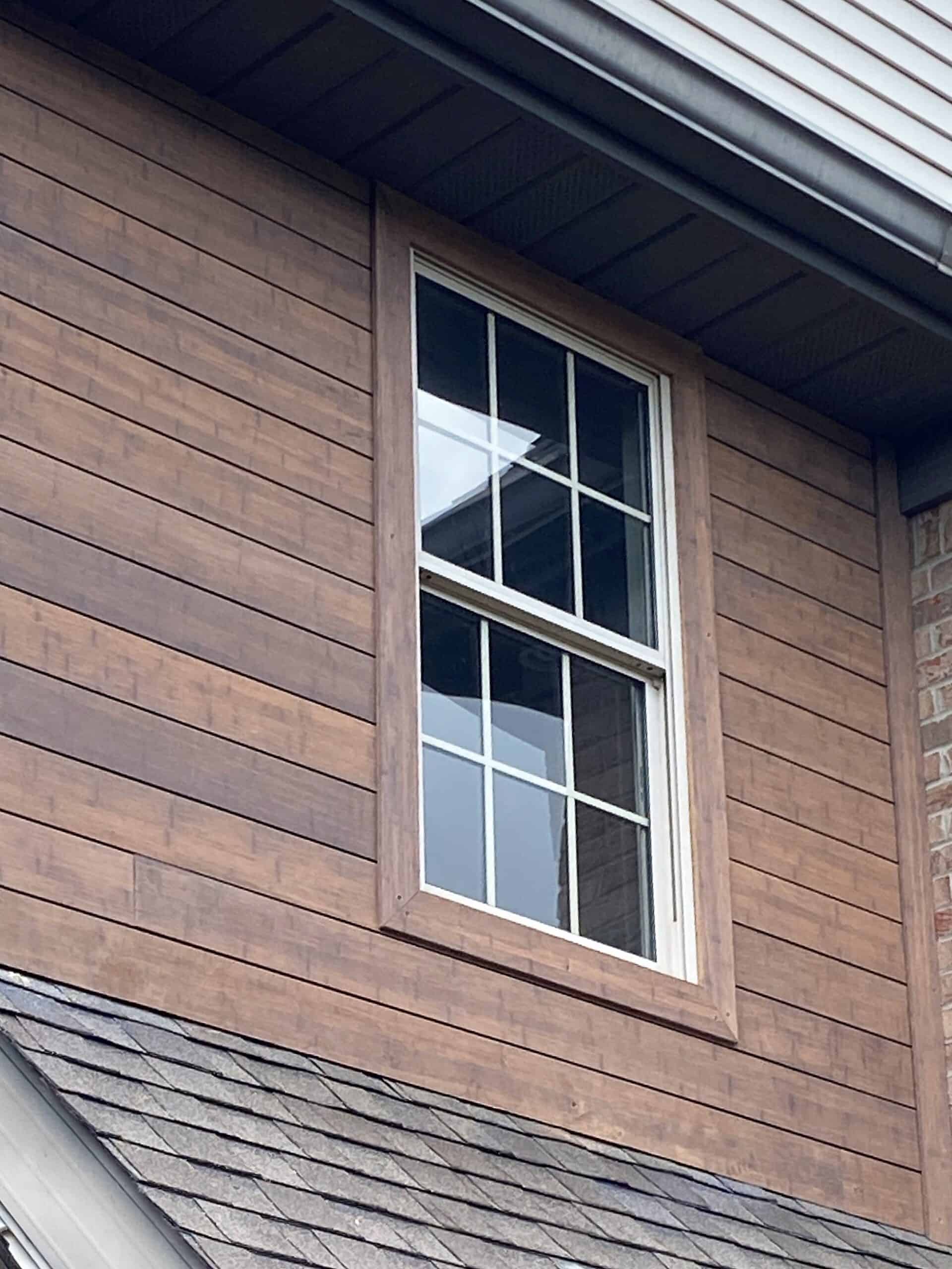 Arten Fenster mit Holzrahmen an einem modernen Haus, Holzverkleidung, Hausfassade aus Holz, Außenfassade mit Holzverkleidung, nachhaltige Hausgestaltung.