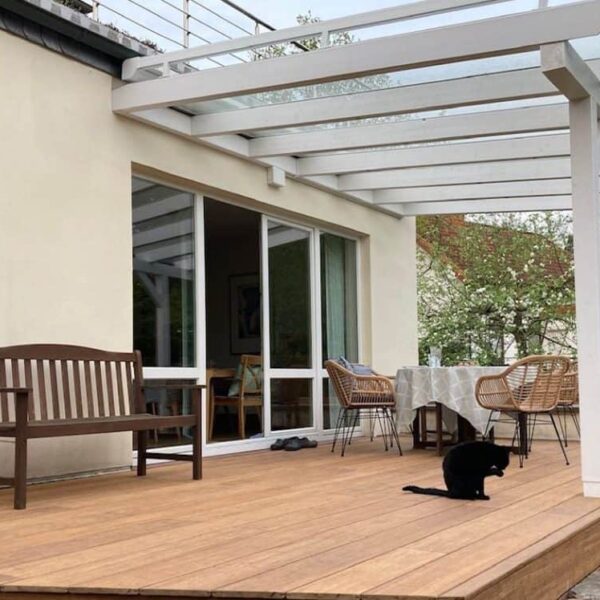 Terrasse mit Pergola, Gartenmöbeln und Katze im Außenbereich.