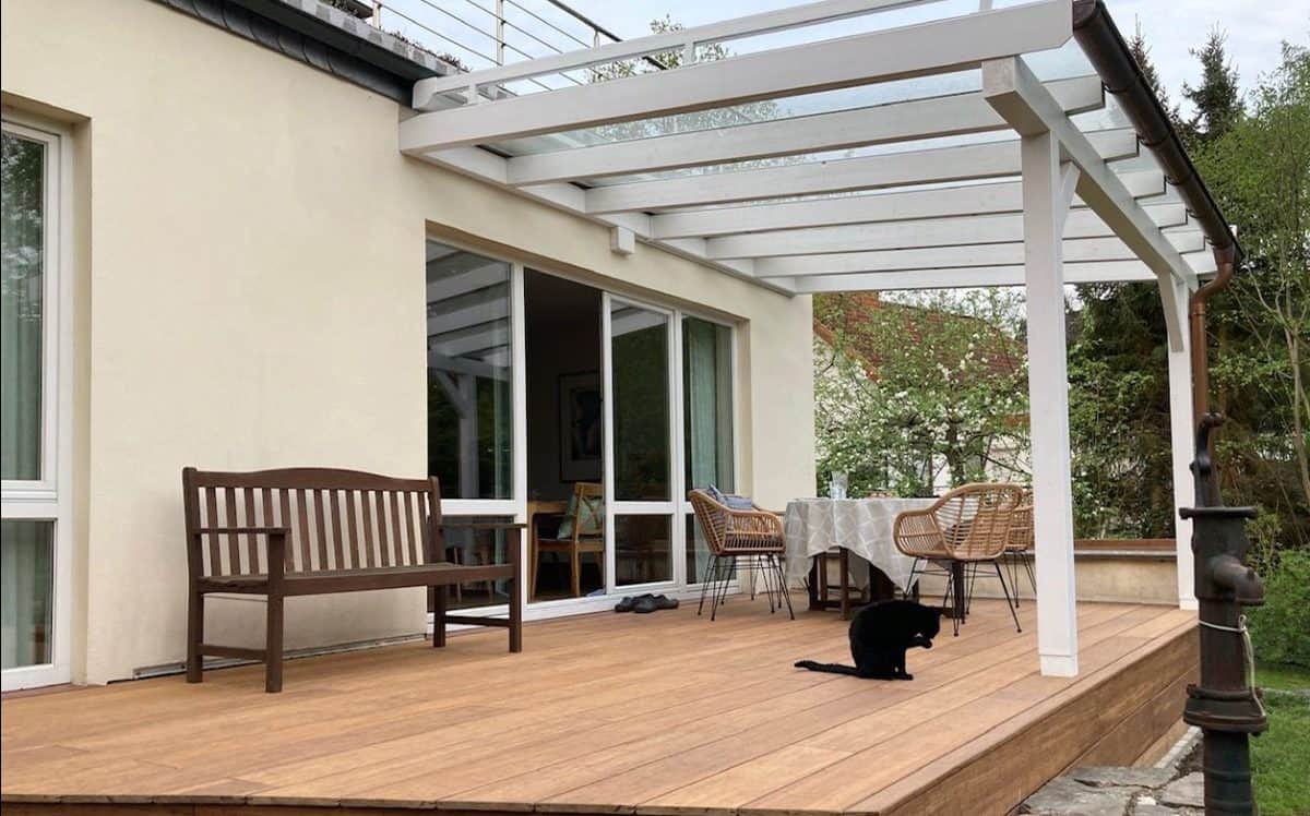 Terrasse mit Pergola, Gartenmöbeln und Katze im Außenbereich.
