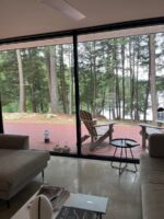 Ferienhaus-Terrasse mit Blick auf den See und umgeben von Bäumen.