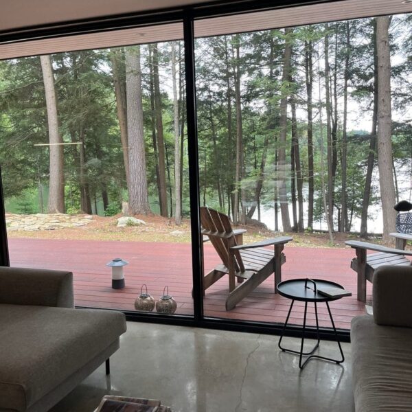 Ferienhaus-Terrasse mit Blick auf den See und umgeben von Bäumen.