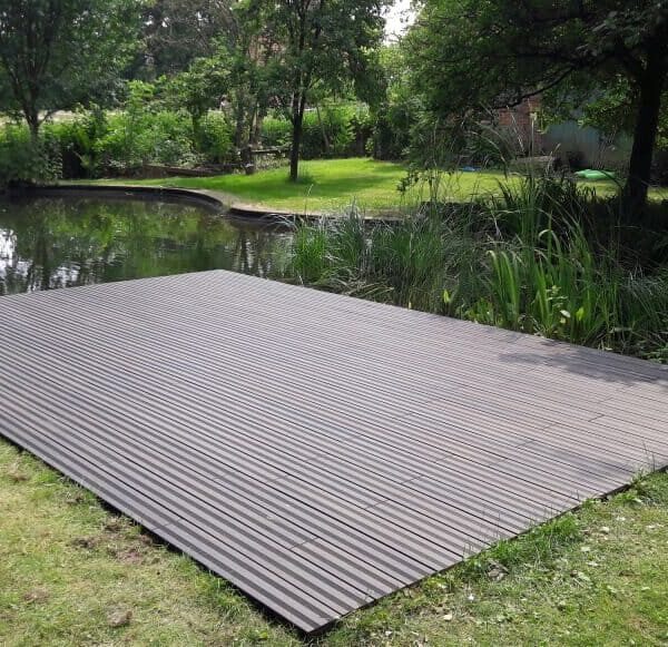 Moderne Holzterrasse am Teich mit Naturumgebung im Garten.