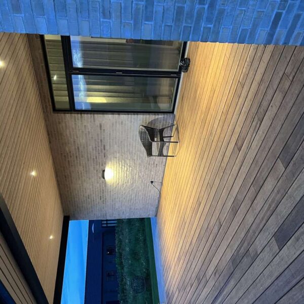 Garten-Terrasse mit Holzdecks, Glaswand und moderner Beleuchtung, ideal für entspannte Abende im Fre.