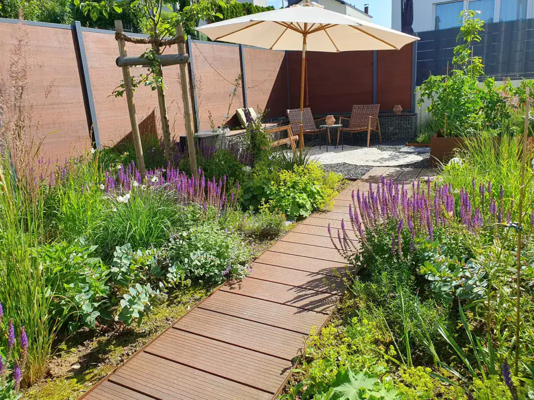 Blumen- und Gartenbereich mit Sitzplatz, Sonnenschirm und gemütlichen Gartenmöbeln.