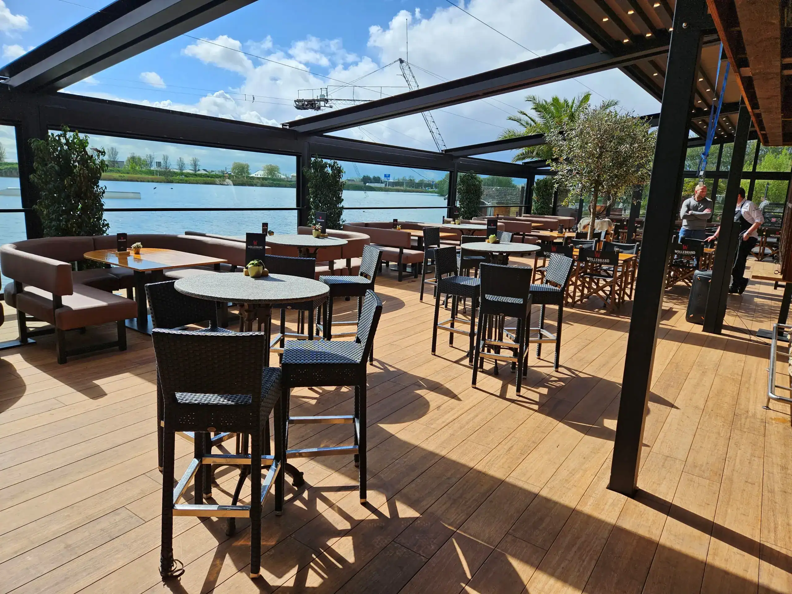 Terrasse mit Blick auf Fluss, Sitzgelegenheiten und Sonnenschutz.